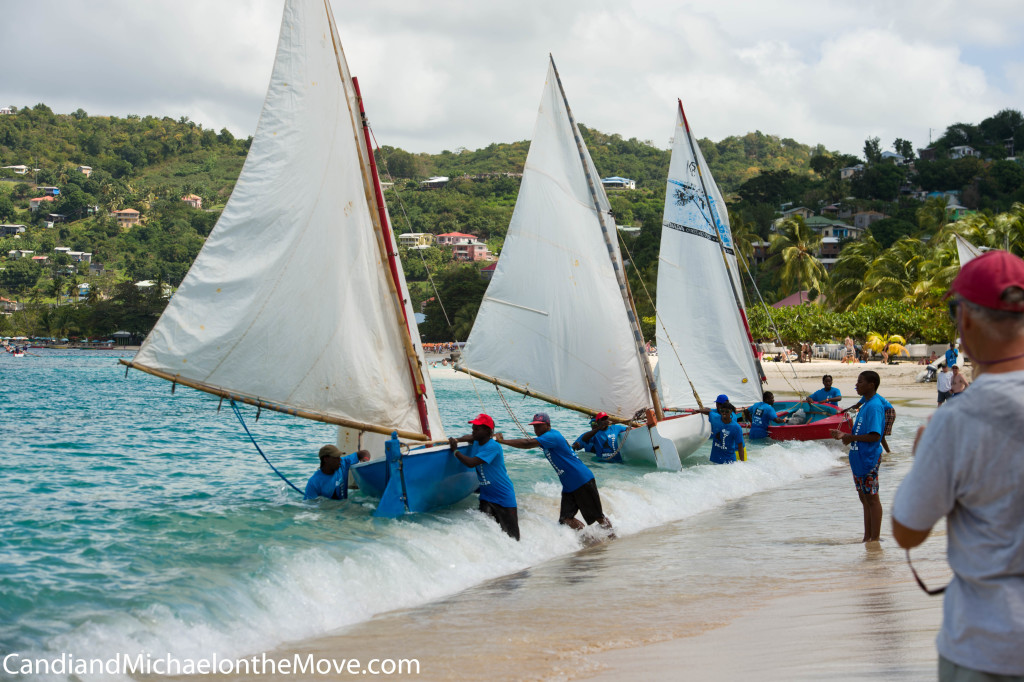 Here, sailors are prepping to sail against each other in acommunity (or village) competition. Thye have pulled and pushed their boats into the surf and are trying to hold them in place until the horn blares, starting the race. Once they hear it, they run pushing their boats into the waves, jumping in at the lasdt minute. The last guy will be almost neck deep in the water when he needs to pull himself up and in.